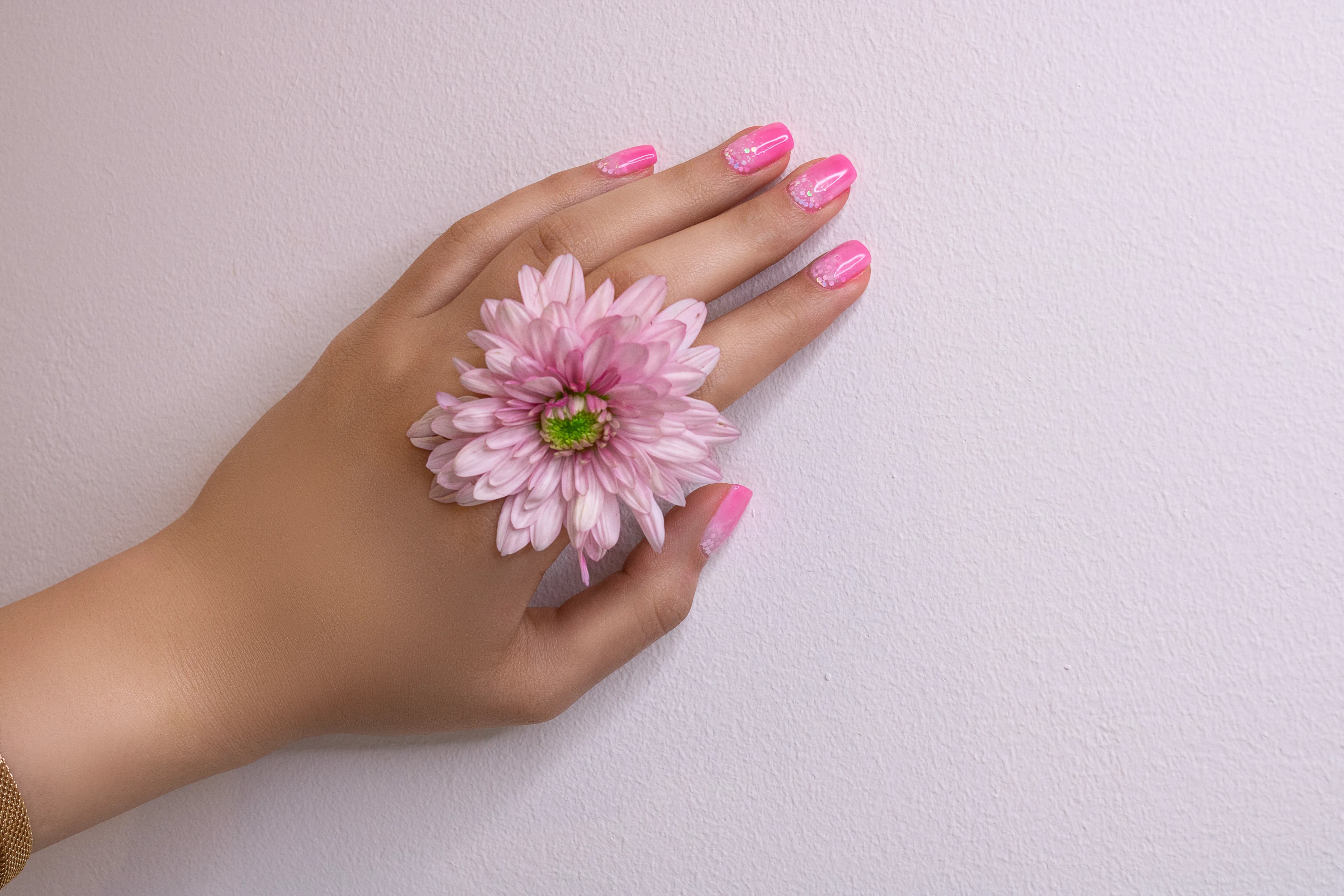 Unhas rosa segurando uma flor