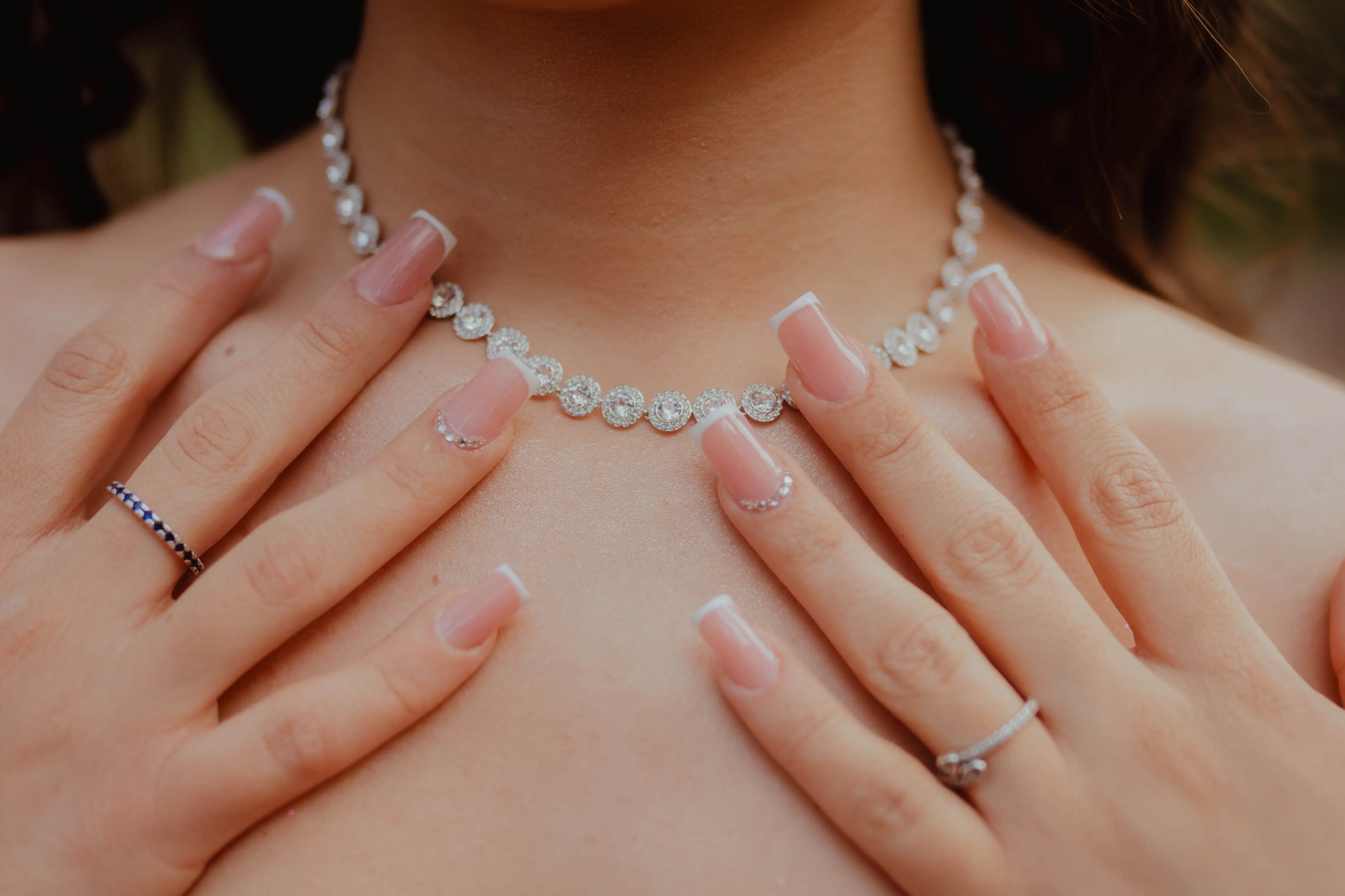 Mãos com unhas delicadas e colar de brilhantes